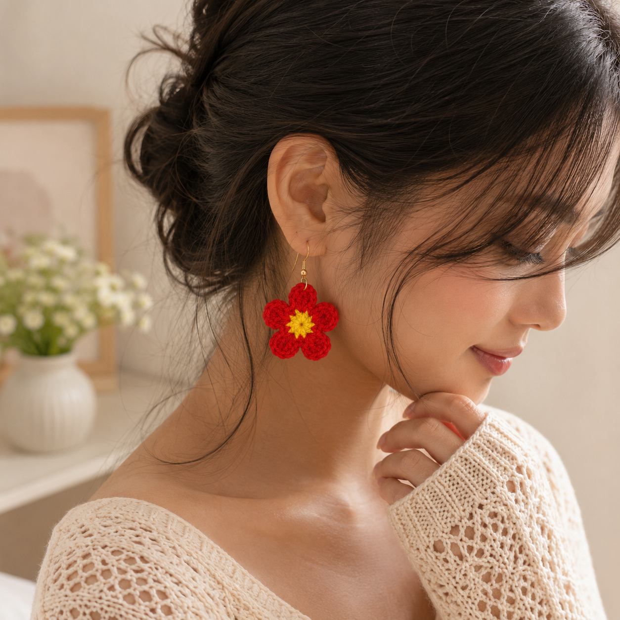 A woman wearing a pair of handmade red flower drop earrings with yellow centers, shown in a close-up profile view.